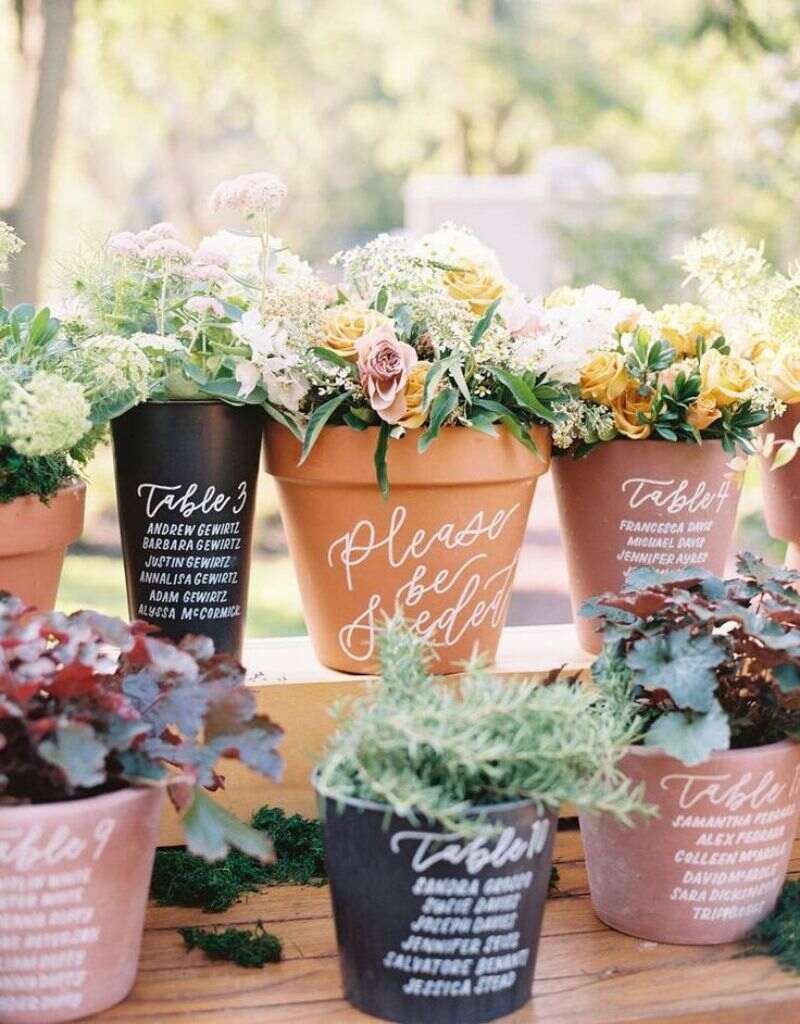 mesas marcadas em vasos de flores