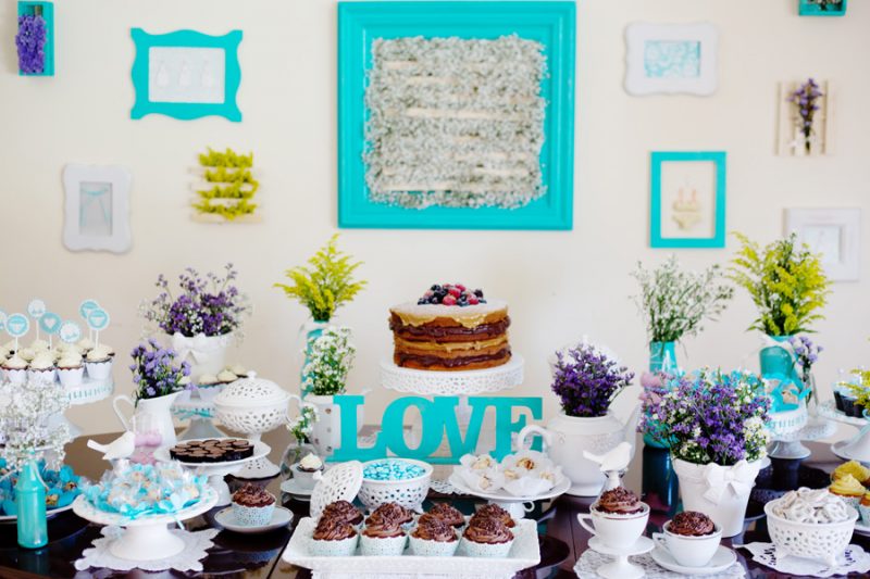 bolo decorado para chá de lingerie em tons de azul com cupcakes na mesa