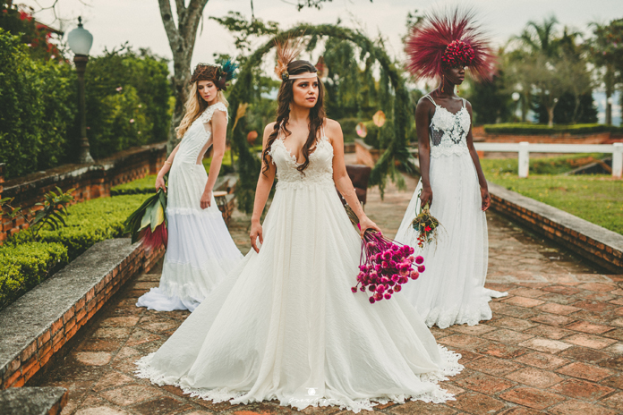 três mulheres usando vestidos de noiva e segurando buquê