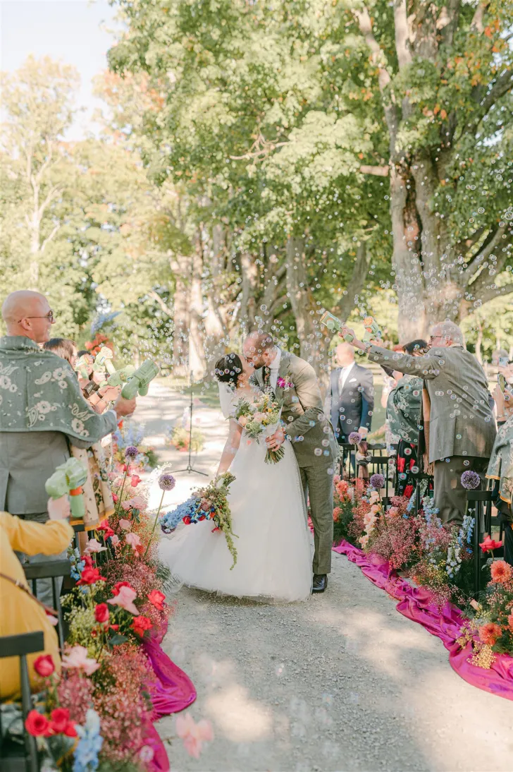 saida dos noivos com beijo em casamento no campo colorido