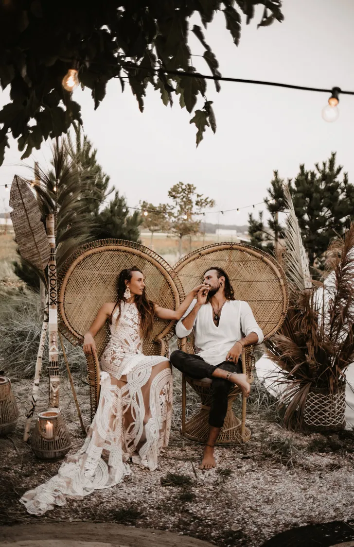 casamento no campo com decoração boho e noivos sentados em cadeira pavão
