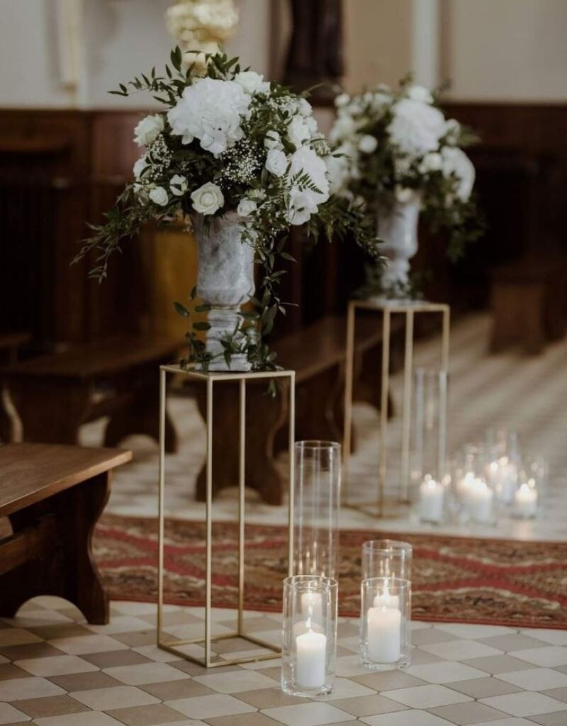 decoração de casamento na igreja com velas e arranjos de flores no final do corredor