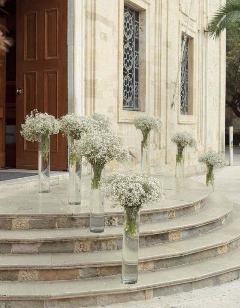 entrada da igreja decorada com vasos de vidro com flor de mosquitinho