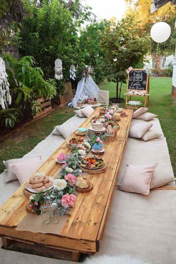 Mesa e almofadas no jardim para celebrar um chá de panela ao ar livre