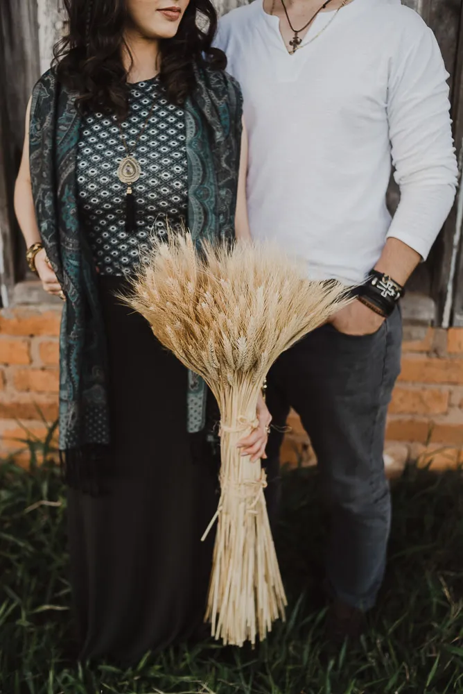 noivos vestidos com look folk em frente a buque de capim dos pampas