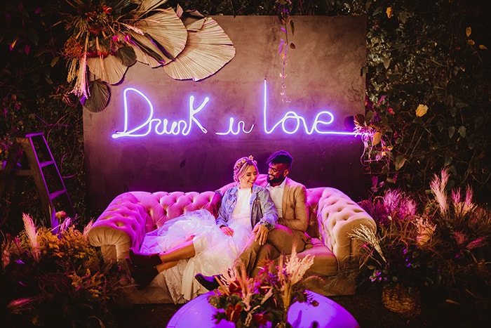 casal em sofá com letreiro neon para decoração de casamento
