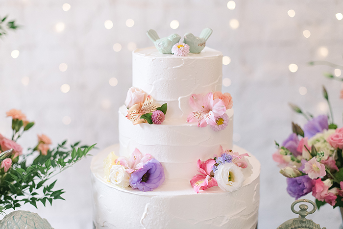 bolo de casamento romântico com topo de flores e passarinhos