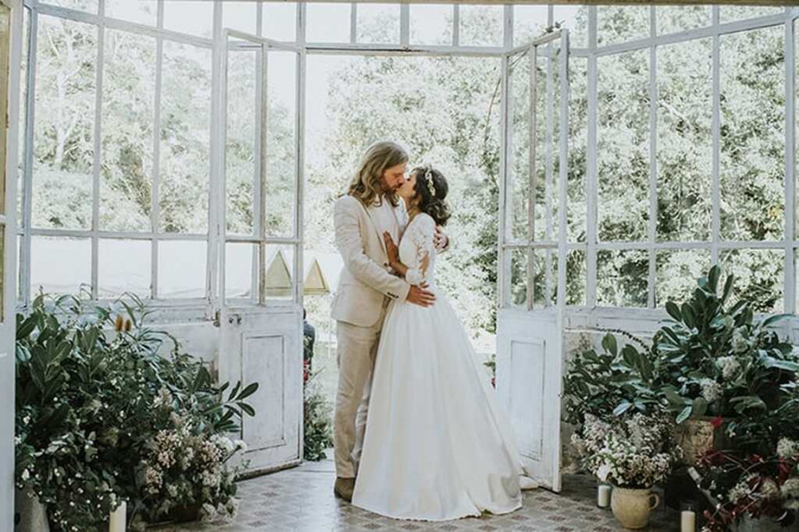 Noivos se beijando em uma casa branca em um casamento sustentável