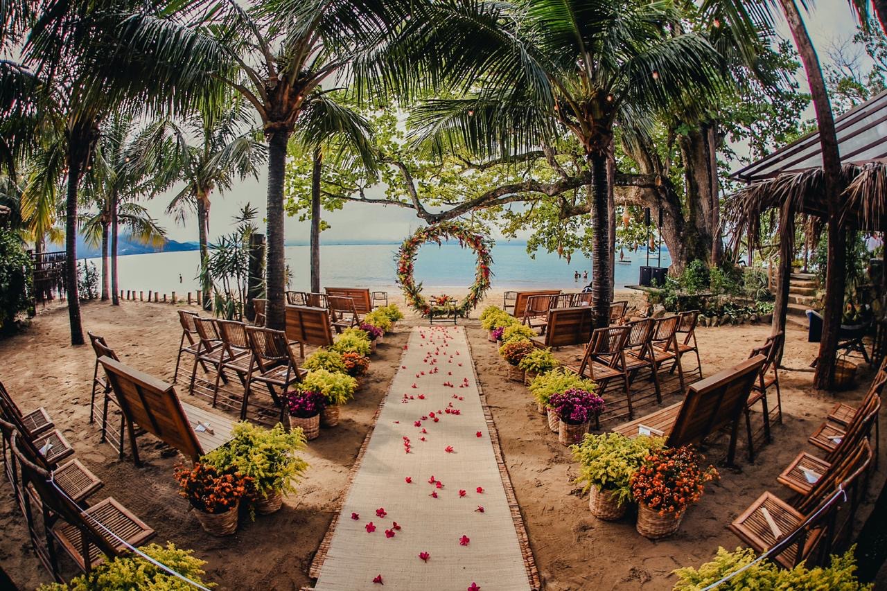 cadeiras de madeira e altar florido par casamento na praia