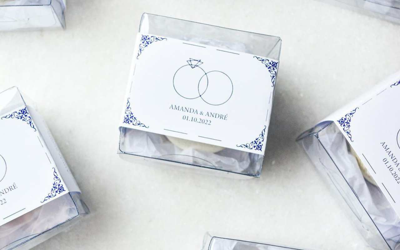 caixinha transparente com uma unidade de macaron branco e rótulo personalizado para lembrancinha de casamento