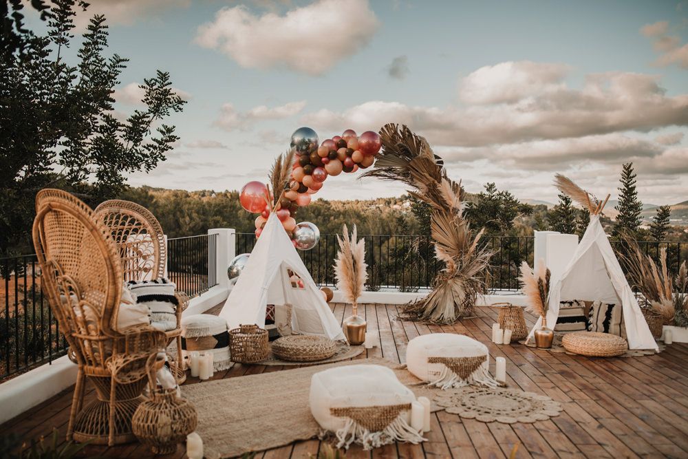 altar circular com folhagens secas e balões com tendas ao redor em casamento boho