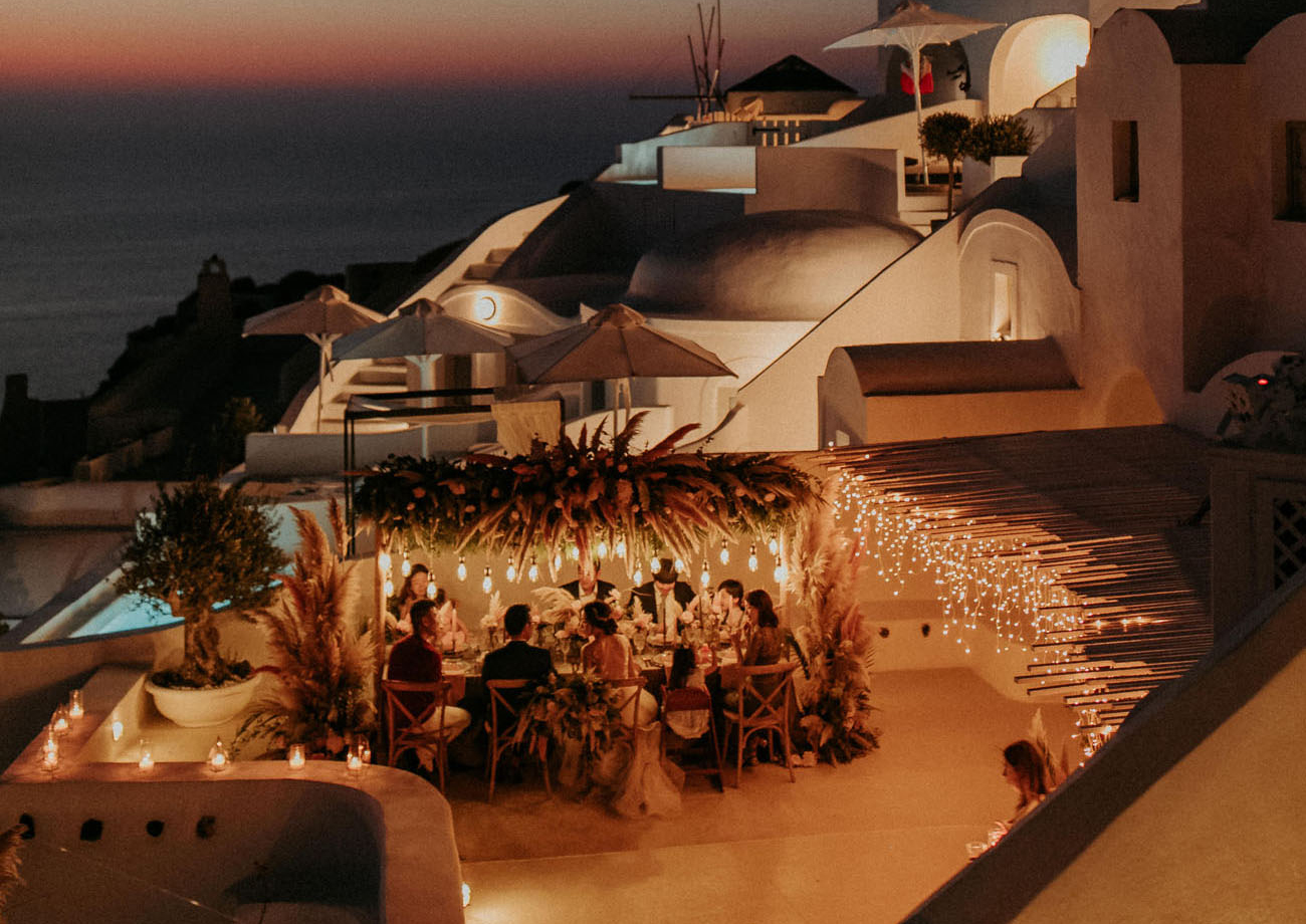 noivos e convidados sentados em uma mesa celebrando um casamento intimista a noite