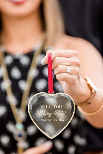 mulher segurando chaveiro em formato de coração escrito will you marry me