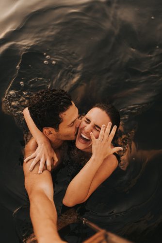 casal nadando no mar enquanto se abraçam