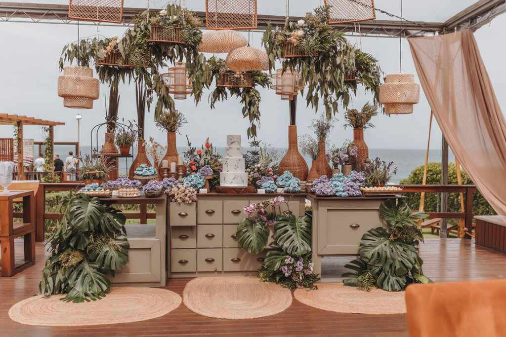 mesa de bolo com arranjos suspensos em casamento na praia 