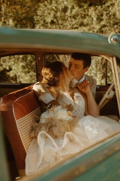 noivos se beijando em carro antigo em casamento vintage