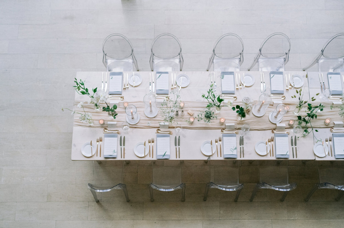 mesa comunitária com cadeiras de acrílico com velas ao centro em casamento minimalista