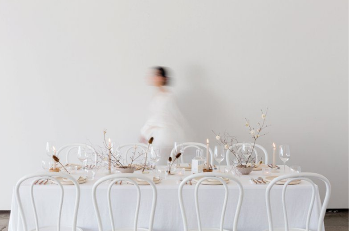 mesa comunitária branca com arranjos ao centro de velas em casamento minimalista