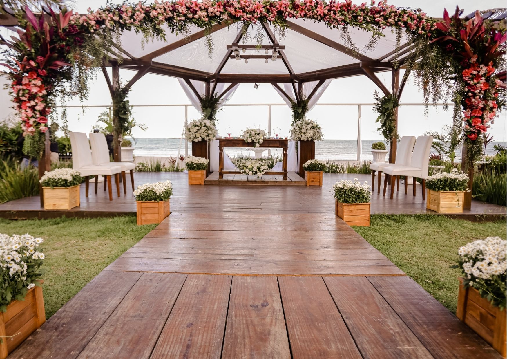 Altar de casamento com madeira, cortina branca e flores
