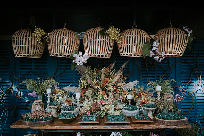 Mesa de decorações com doces, flores e luminárias