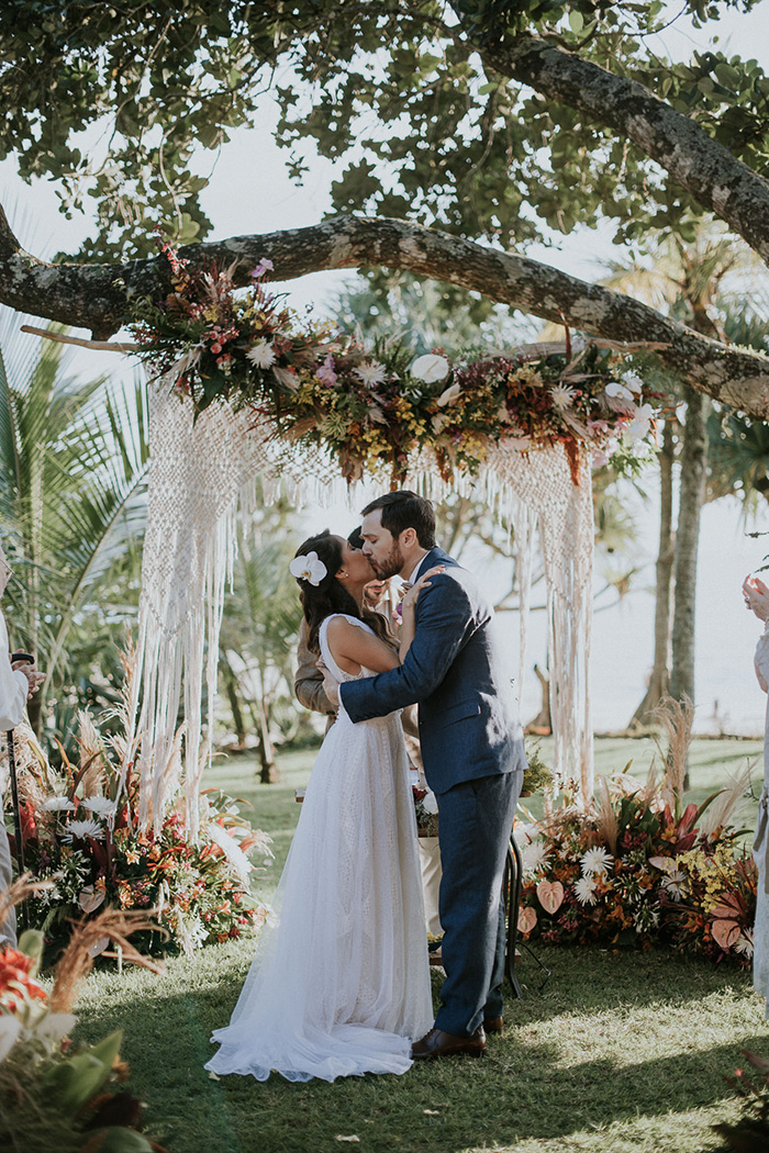 Noivos se beijando em frente a altar florido