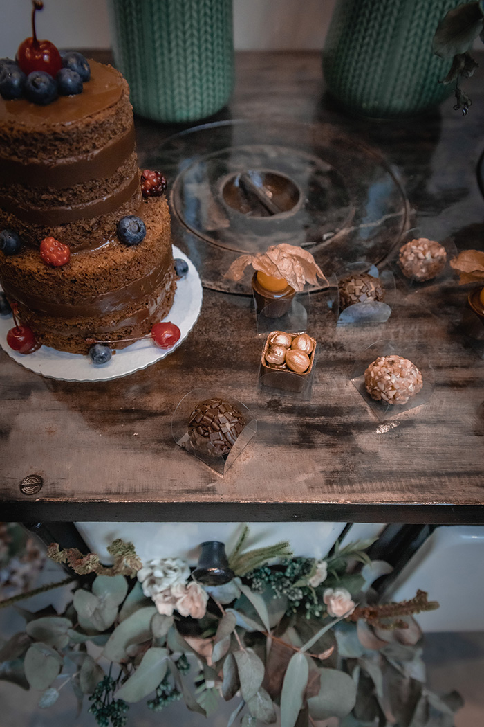Mesa de madeira com doces e bolo de chocolate