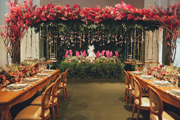 Mesa para convidados e mesa do bolo com arco de flores