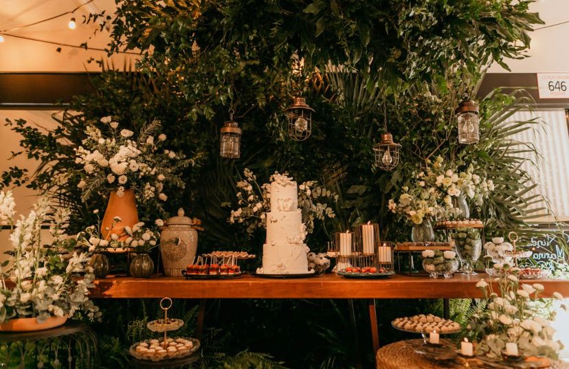 Mesa de madeira com bolo de casamento e plantas