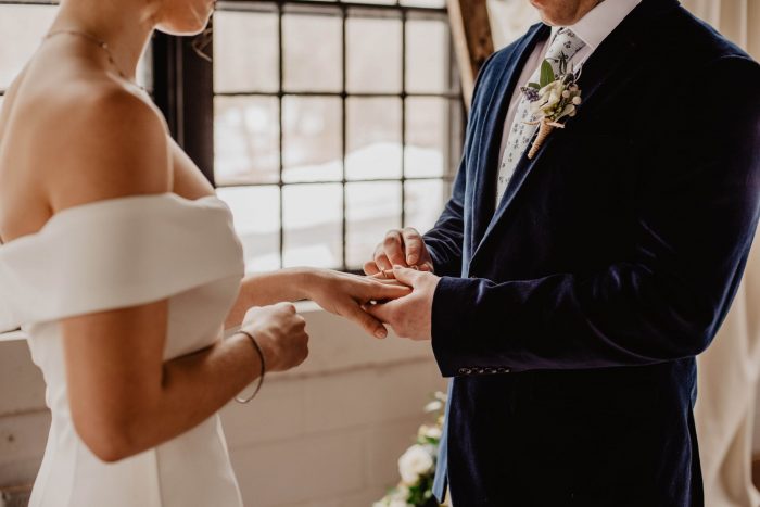 Noivo colocando aliança no dedo da noiva