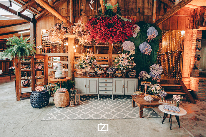Salão de madeira com flores pendentes e mesa com doces