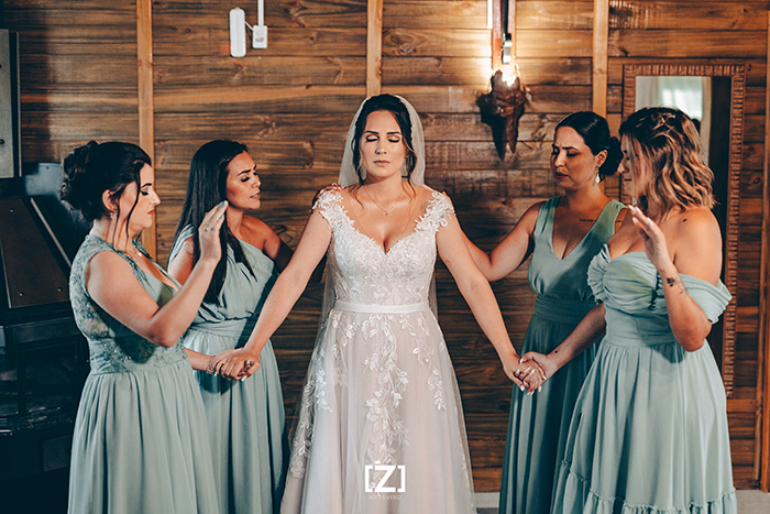 Madrinhas de vestido azul rezando com a noiva
