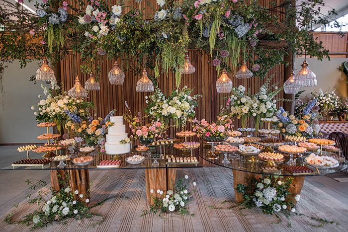 Mesa com doces, bolo de casamento e flores