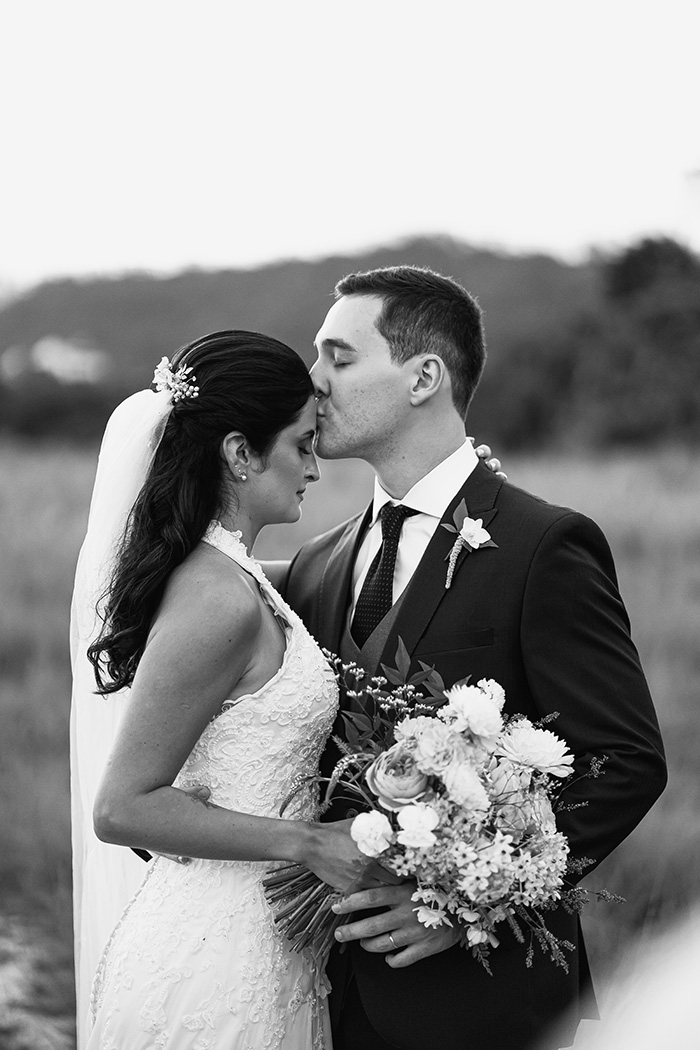 Noivo beijando testa da noiva no campo