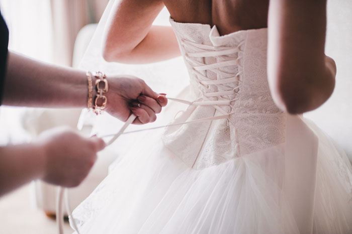 Mulher ajudando a fechar corset da noiva