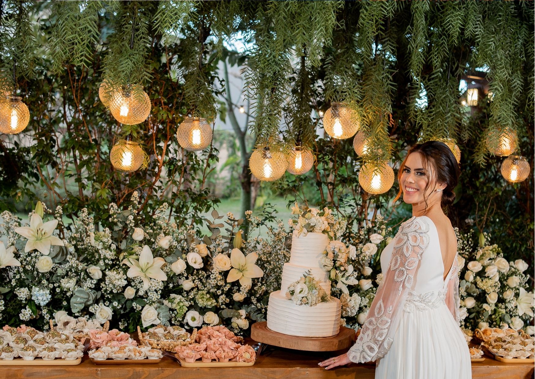 Noiva em frente a mesa com bolo de casamento
