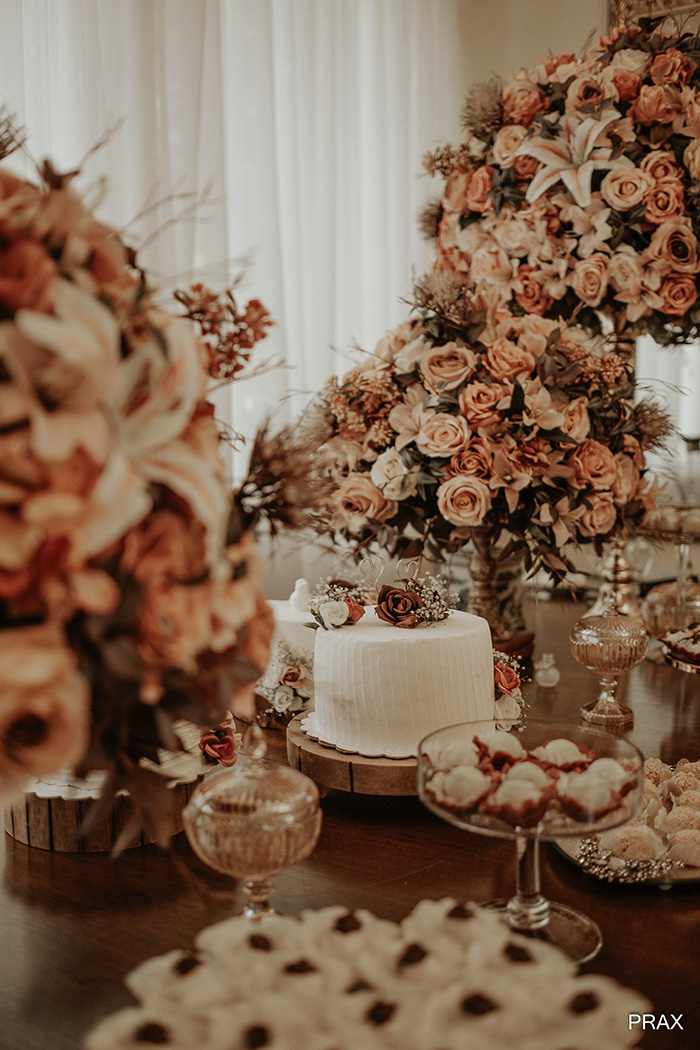 Mesa com flores rosas e laranjas e bolo de casamento