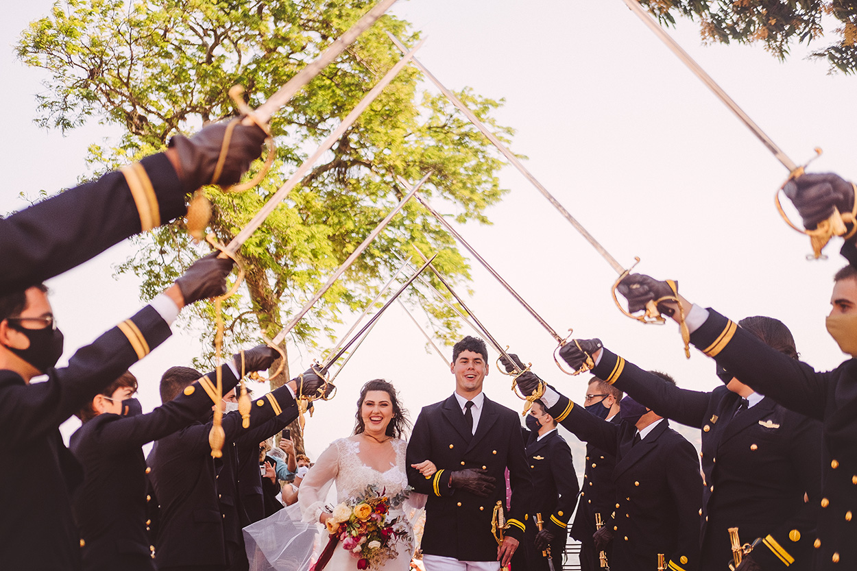 Homens com espadas e noivos sorrindo