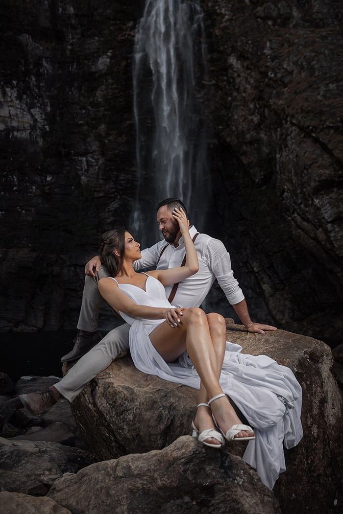 Noivos sentados na pedra na cachoeira