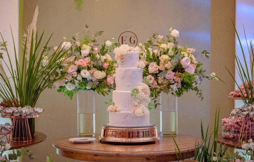 Mesa com bolo de casamento branco de 4 andares
