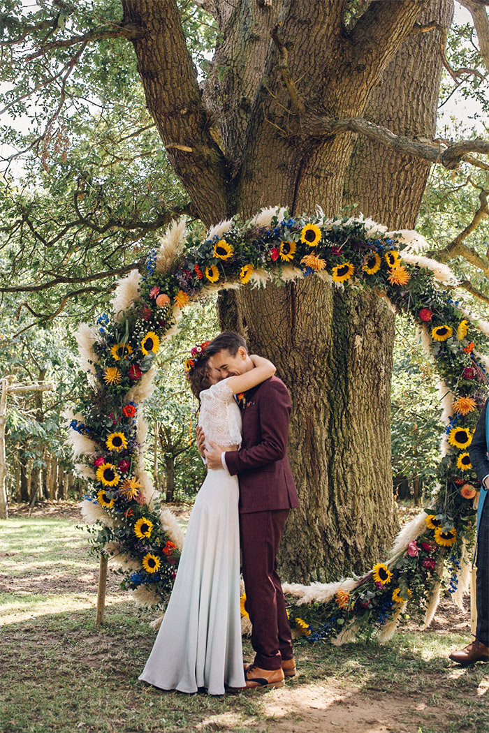 noivos se beijando em altar circular de girassóis