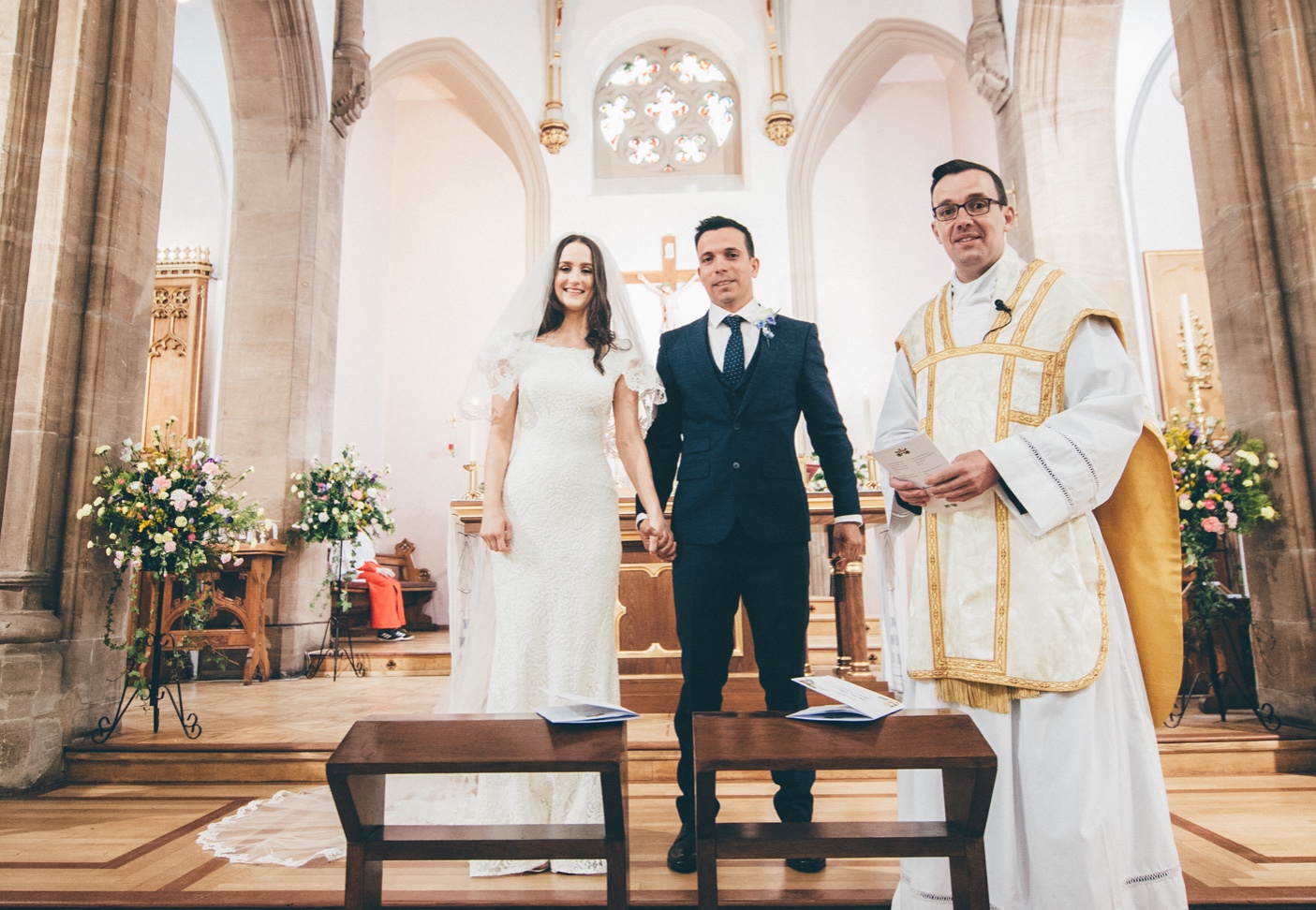 noivos ao lado do padre em casamento na igreja católica 