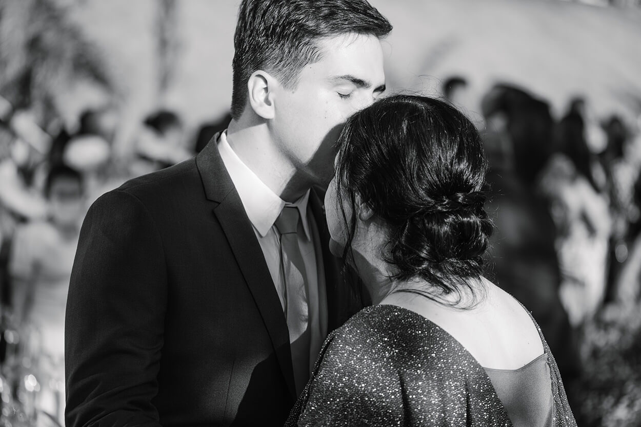 Noivo beijando a testa da mãe no casamento