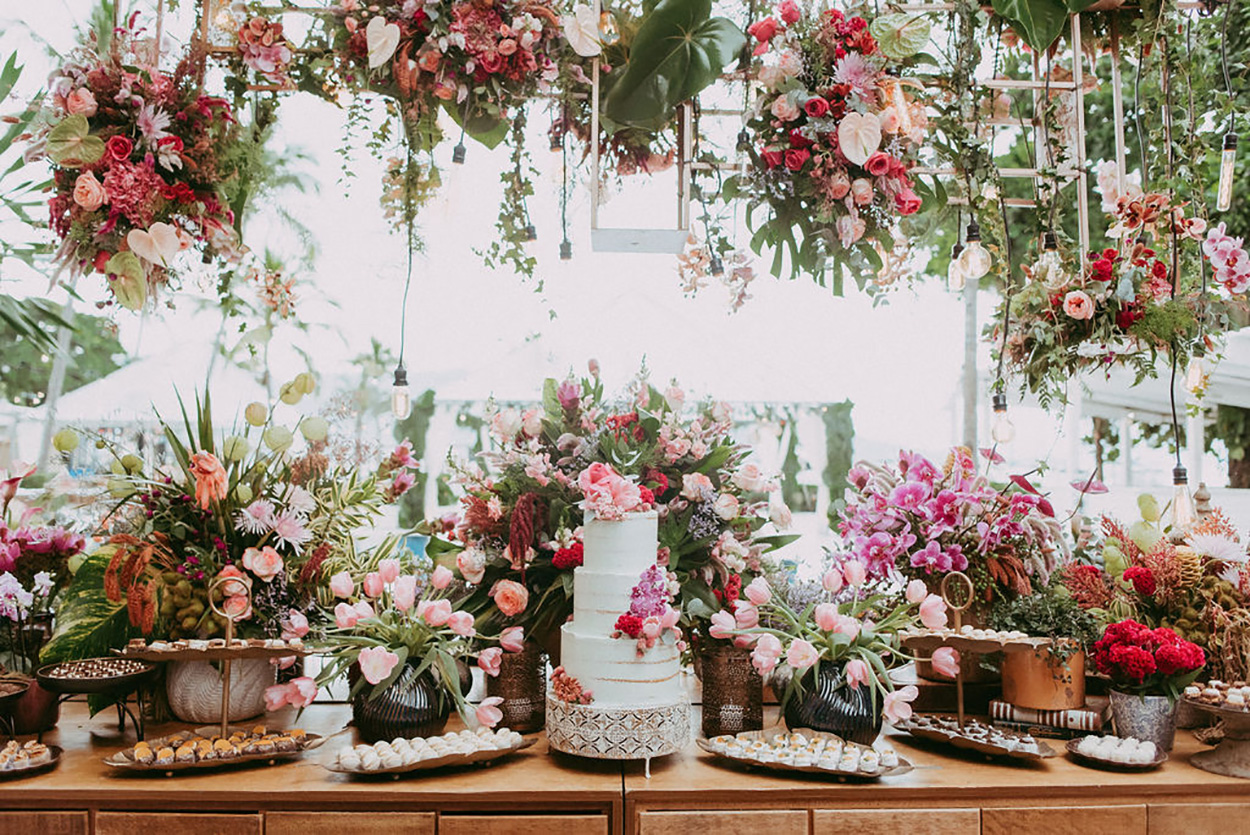 Mesa decorada com flores e bolo de casamento branco