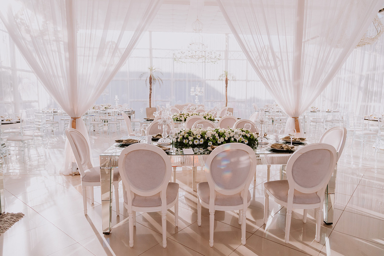 Salão com mesas decoradas com branco