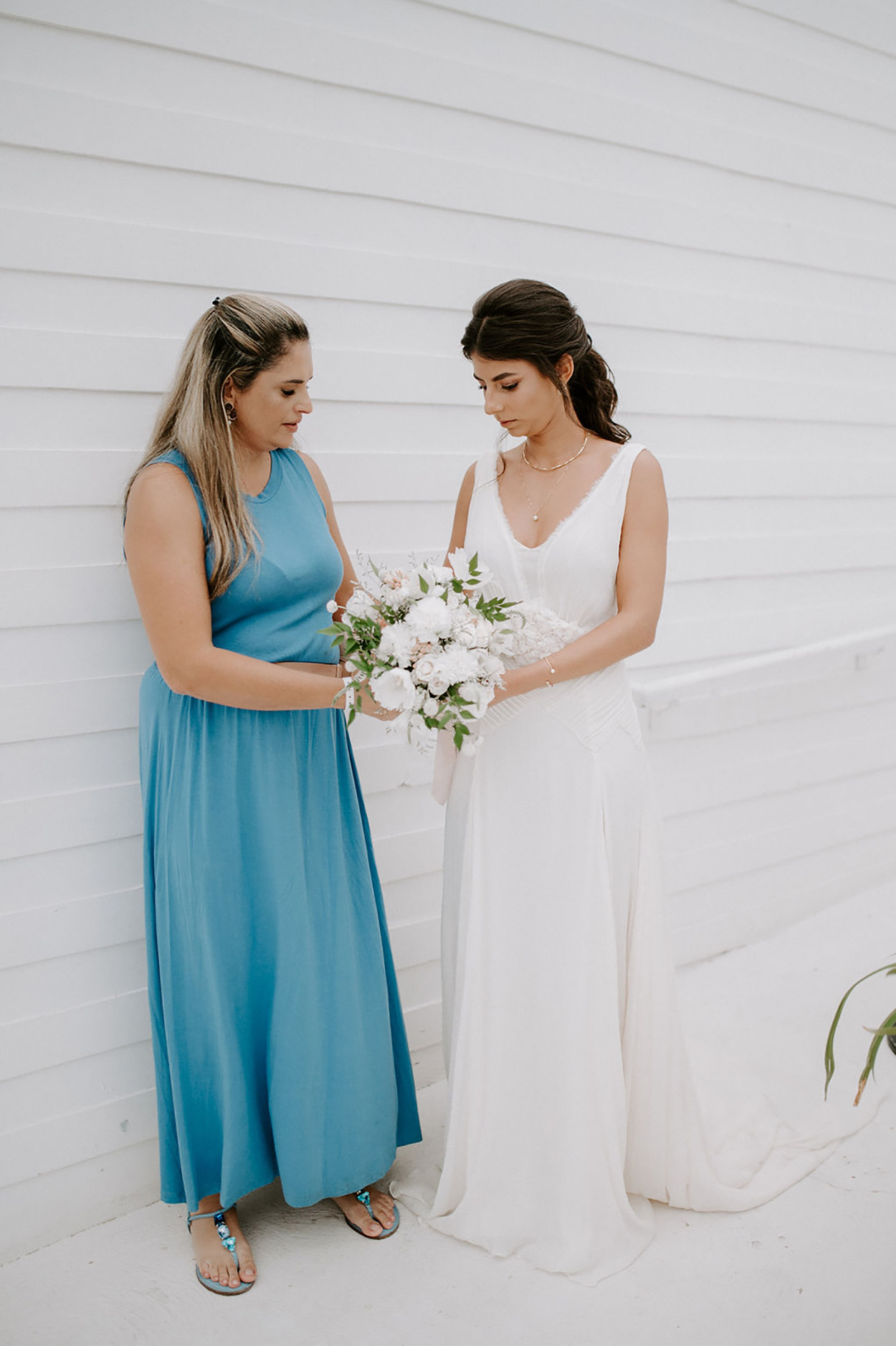 Noiva com buquê e mulher de vestido azul