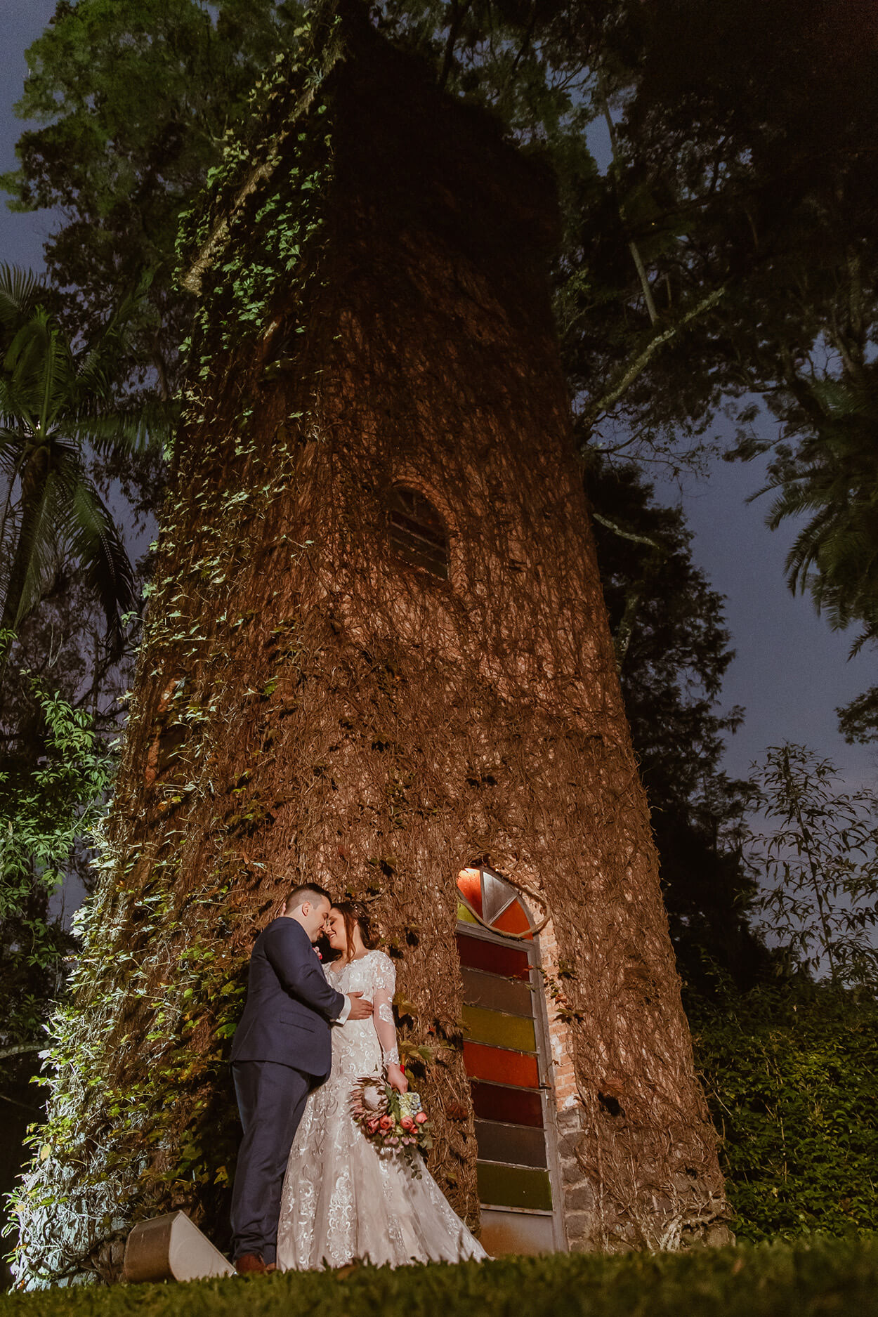 Noivos abraçados perto de torre rustica
