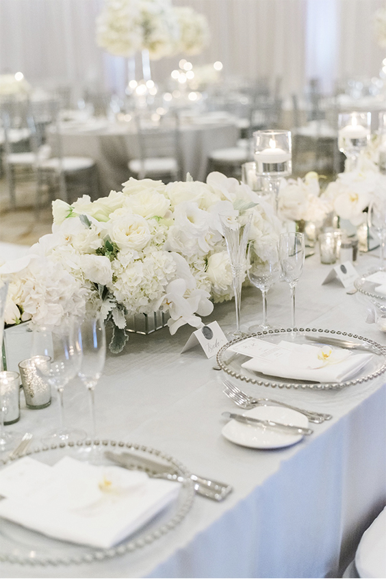 mesa com arranjos ao centro com flores brancas para bodas de prata
