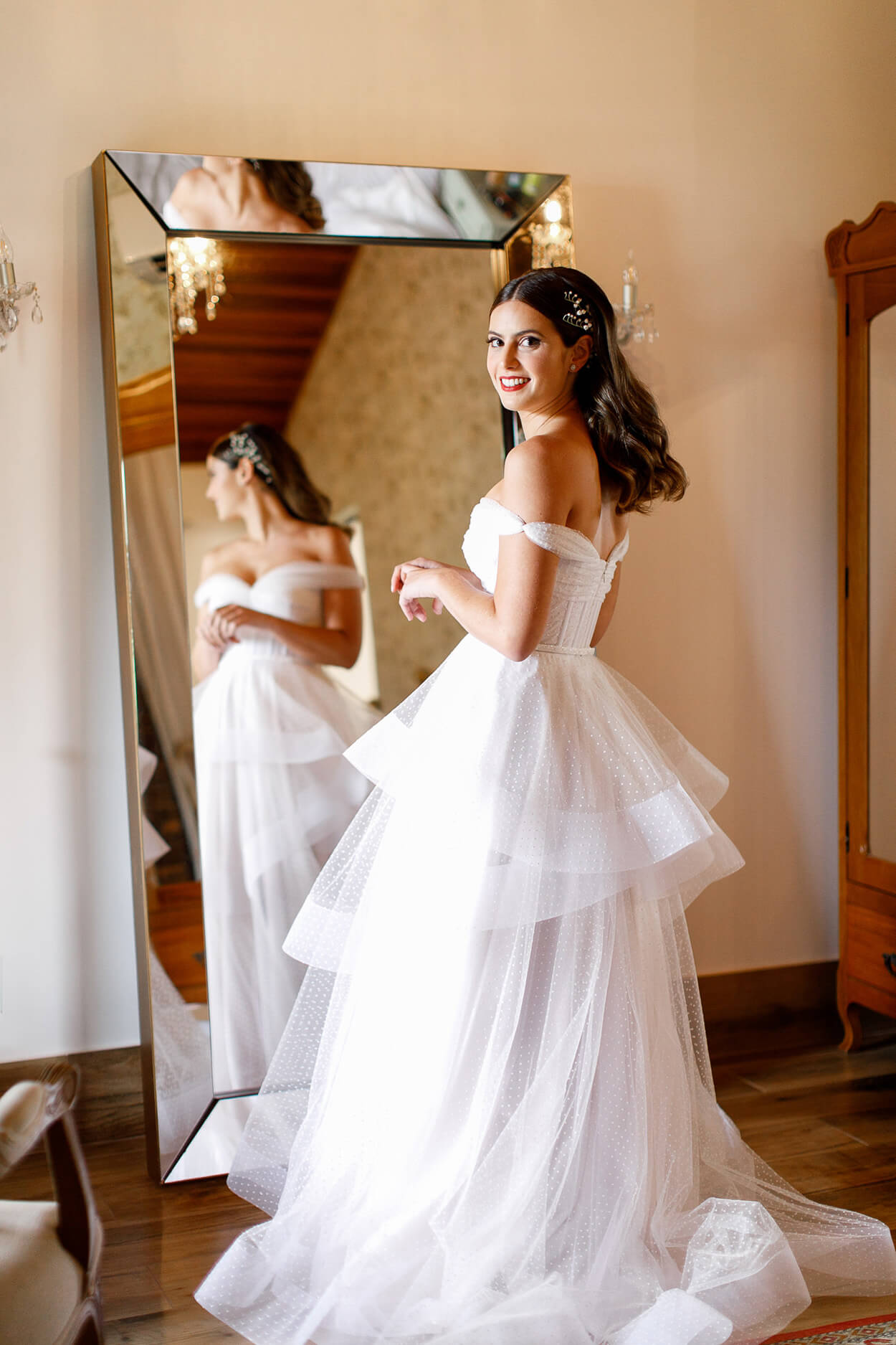 Mulher com vestido de noiva com camadas esvoaçantes de tule em frente ao espelho
