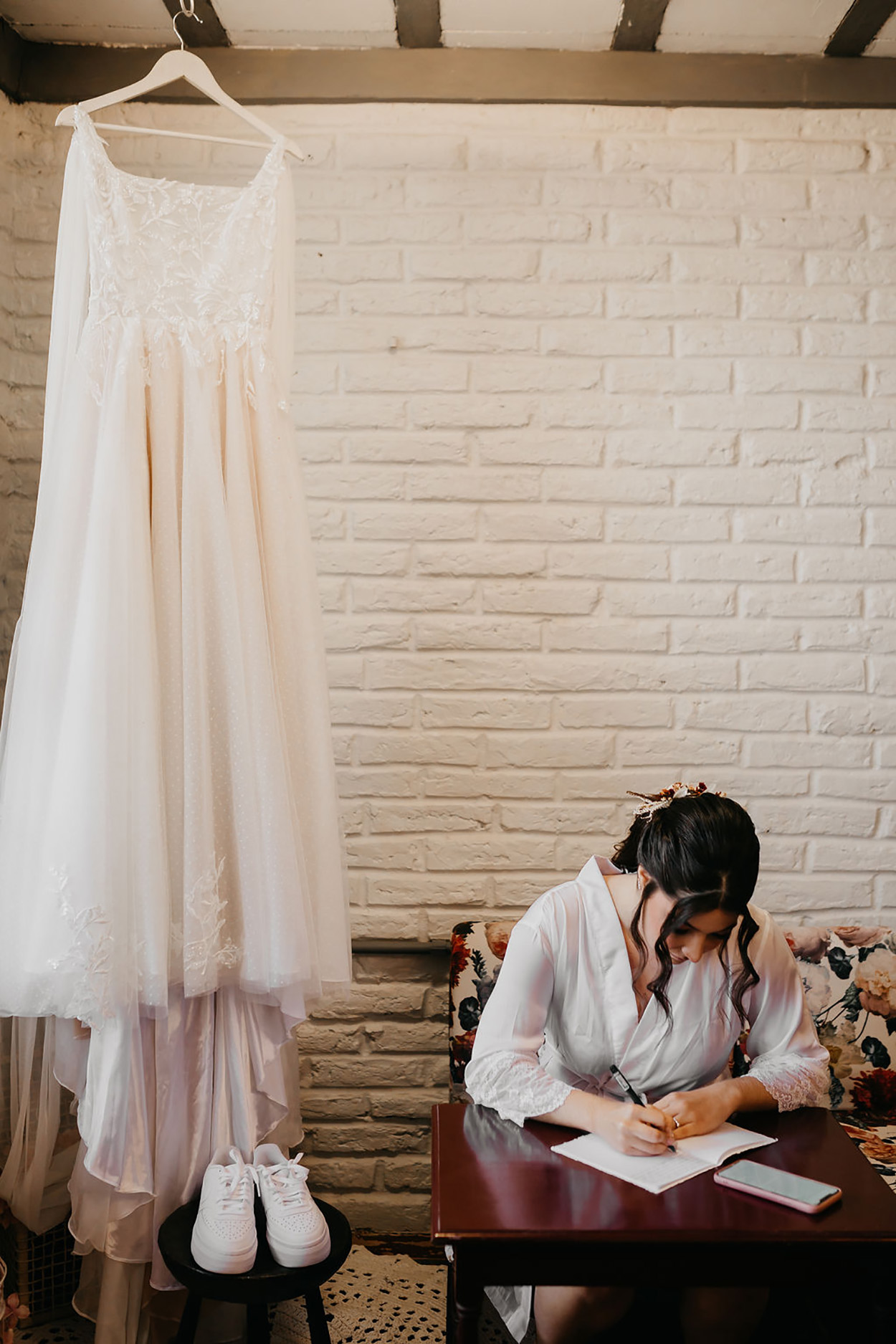 Mulher escrevendo perto de vestido de noiva