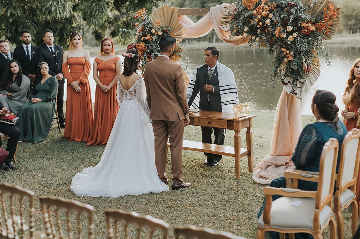 Noivos e convidados no casamento no jardim perto do lago